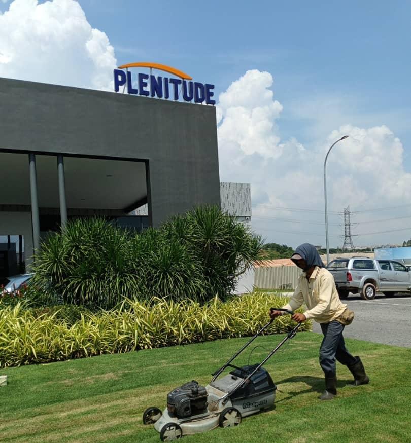Worker mowing lawn in front of Plenitude corporate building