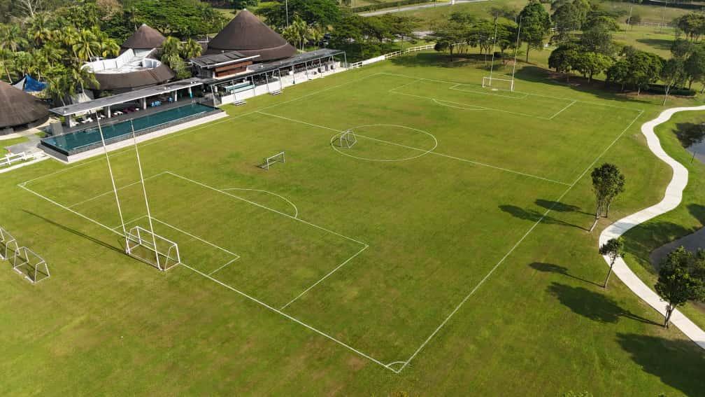 Aerial view of a manicured sports field with clubhouse and pool at Leisure Farm