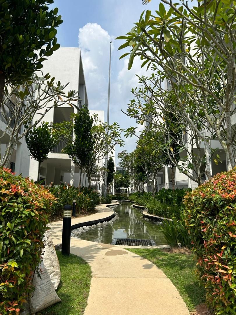 Landscaped water channel walkway between residential buildings with plumeria trees